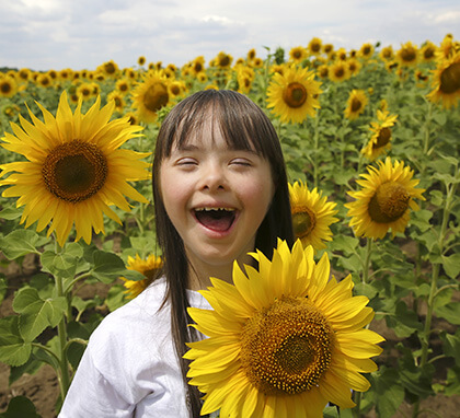 Young girl smiling outside in a field of beautiful sunflowers