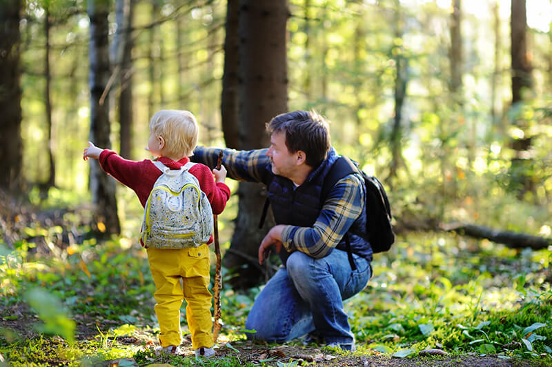 Parent and child outside in a forest wearing backpacks